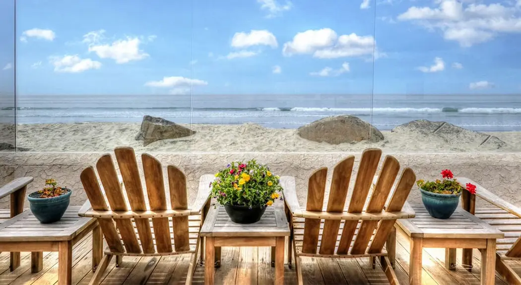 Two beach chairs on a patio overlooking the beach.