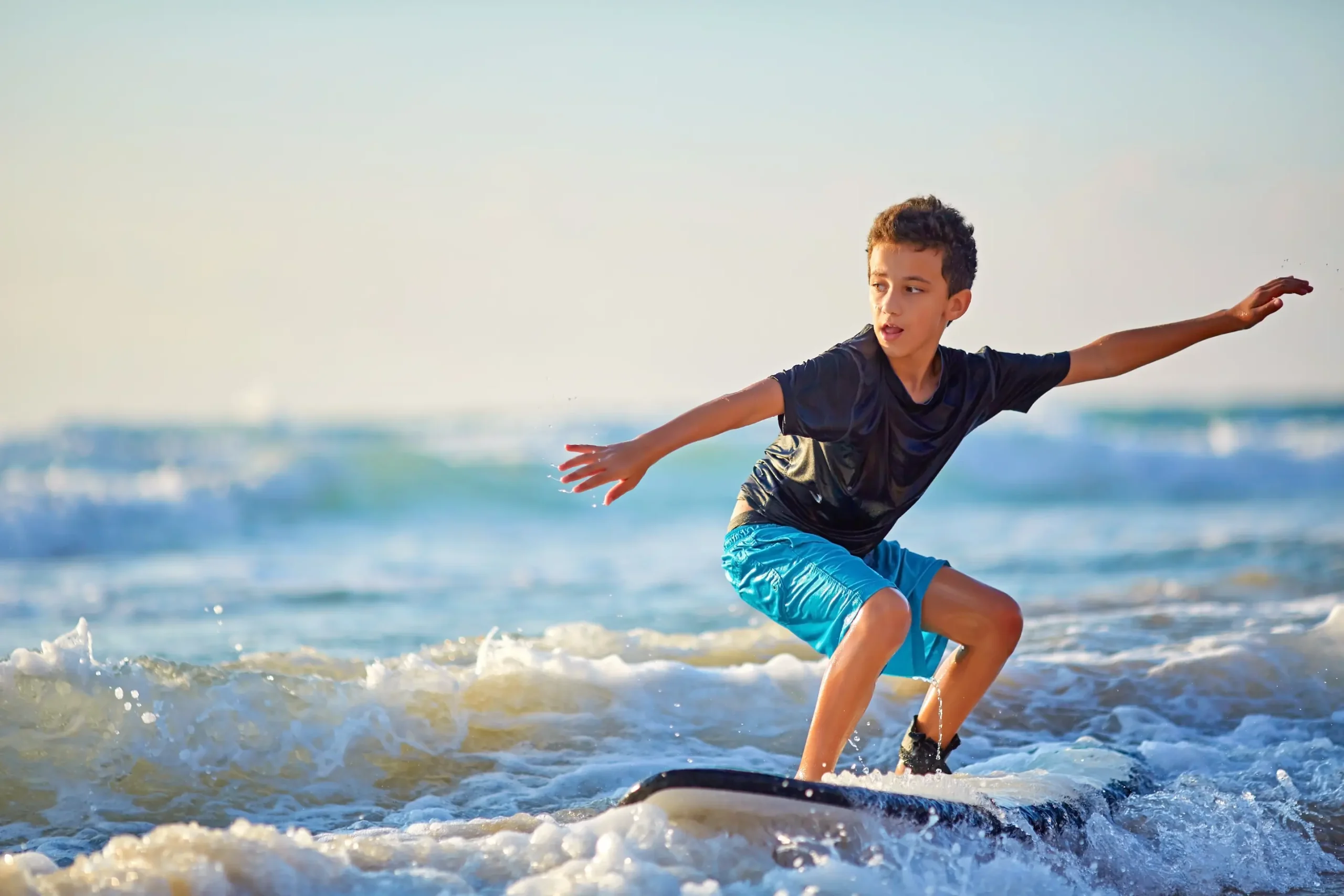 Skilled teenager riding surfboard and balancing a long wavy sea