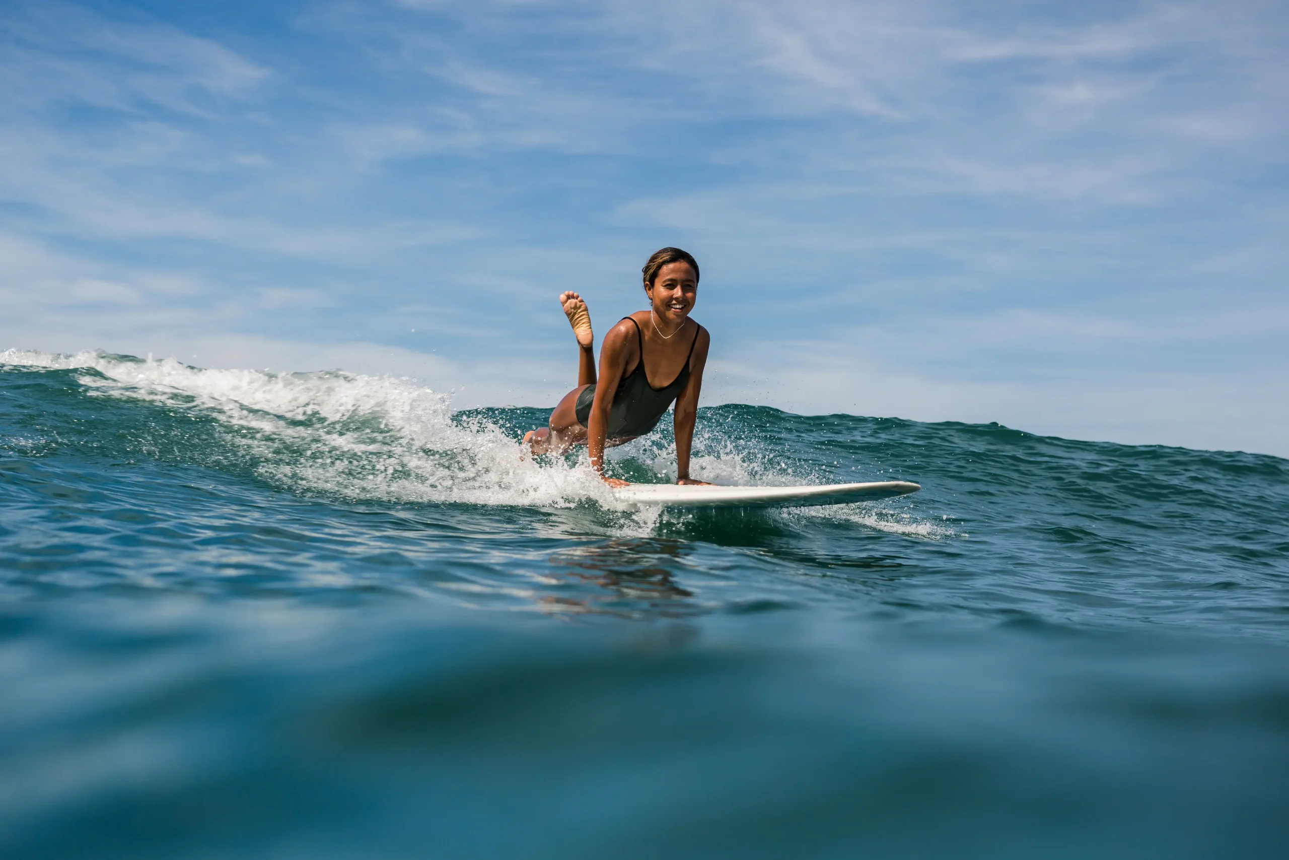 Woman striking plank pose while surfing.