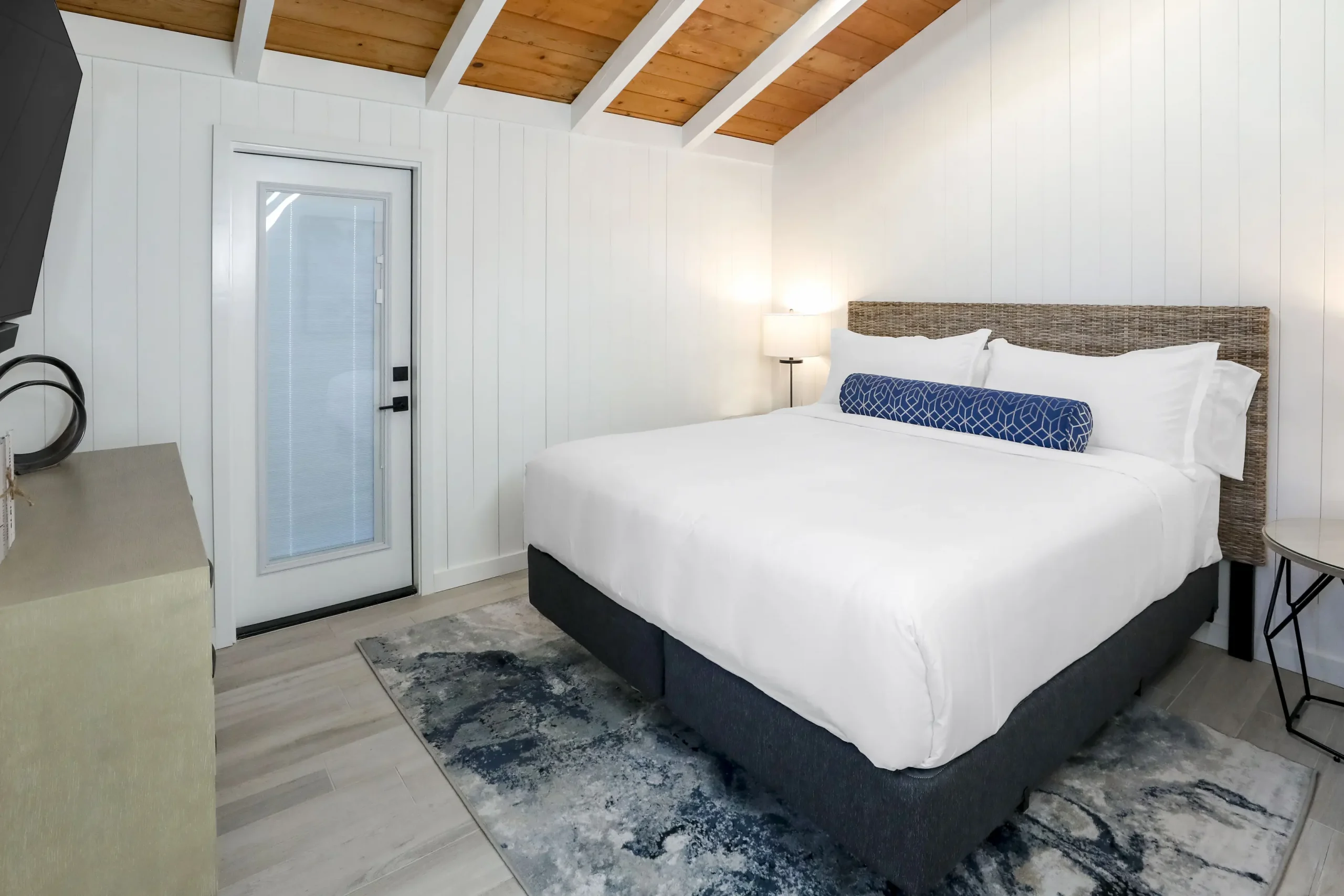 beach cottage guestroom. Bed with blue accent pillow and ocean artwork